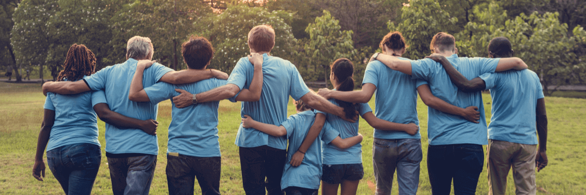 group of volunteers walking in a field, arm in arm, non profit organization concept